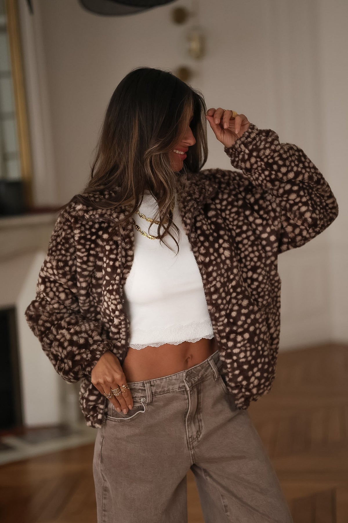 Veste polaire marron Nyla à imprimé bambi, portée ouverte avec un top blanc, une main levée